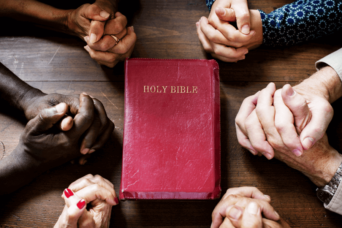 people praying around the bible