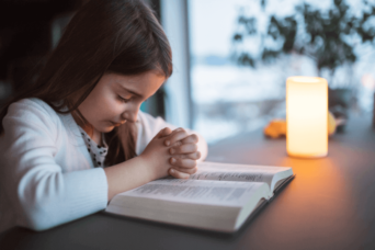 young girl praying with the bible