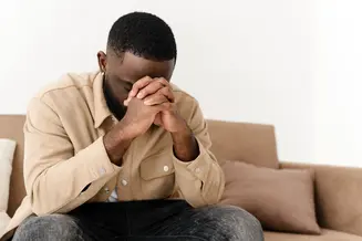 african american man praying on sofa