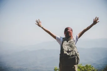 woman hiker on mountain hands up