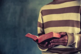 man standing while reading the bible