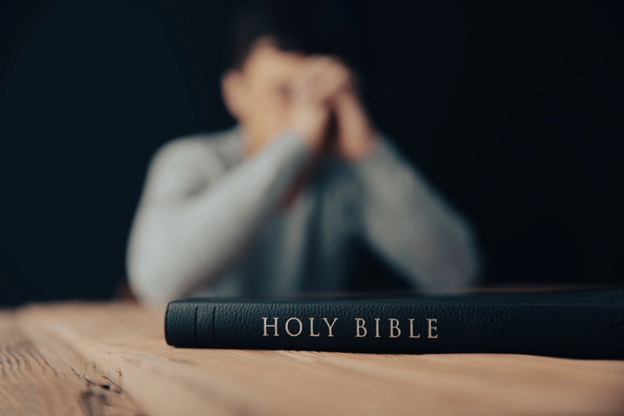 man praying with holy bible