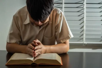 young boy praying bible