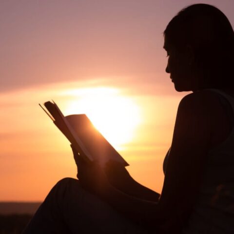 woman reading bible sunset