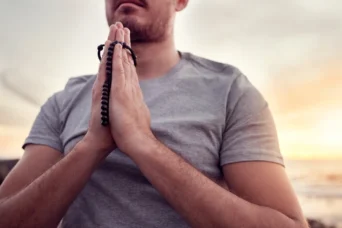 man praying with rosary in hands