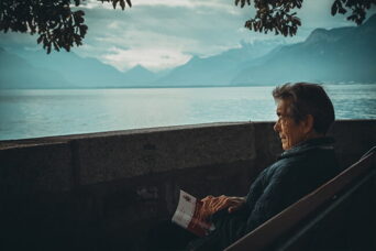 man reading a book by the lake