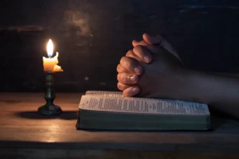 woman praying bible candle light