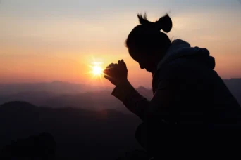woman praying in the sunset